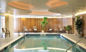 a large indoor pool surrounded by lounge chairs , where people are relaxing and enjoying their time at Garden City Hotel
