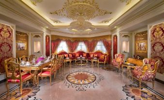 a large dining room with red and gold decor , including chairs , tables , and a central table at Royal Rose Abu Dhabi