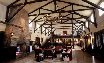 a spacious , well - lit hotel lobby with high ceilings , wooden beams , and various seating arrangements , including couches , chairs , and dining at Disney Hotel Cheyenne
