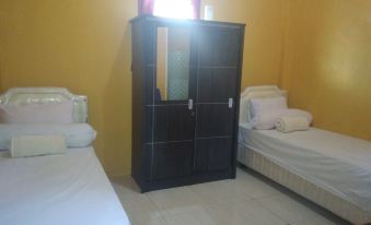 a room with two beds , a black wardrobe , and white bedding , giving it a cozy and inviting atmosphere at Sinar Harapan