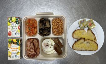 a tray of food with various items including beans , sausage , toast , and a carton of eggs at Raintree Motel