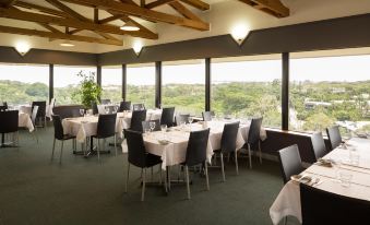 a dining room with tables and chairs arranged for a group of people to enjoy a meal at Frontier Hotel Darwin