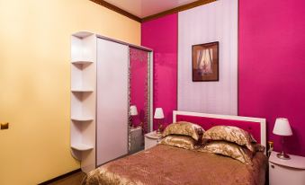 a bedroom with a pink and yellow color scheme , featuring a bed , nightstands , and a closet at Diana