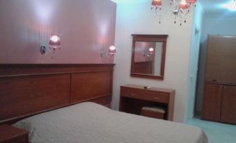 a bedroom with a bed , nightstand , and mirror , along with pink walls and a chandelier at Paradise