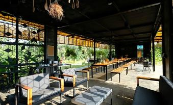 a modern , open - air restaurant with wooden tables and chairs arranged around them , creating an inviting atmosphere for customers at Baan Rai Darun Home Stay and Scenery Raft