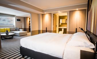 a large bed with white sheets is in a room with a black and white striped rug at Simon Hotel