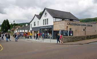a group of people are walking down a street in front of a store named caledonian inn at Lock Chambers, Caledonian Canal Centre