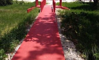 a red walkway leads to a beach with greenery and a small wooden structure in the foreground at Holiday Inn Beach Resort
