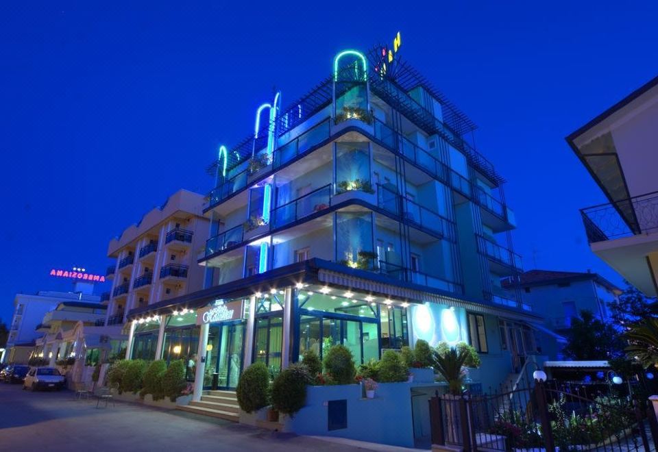 a large hotel building with a blue and green facade is lit up at night at Hotel Hamilton