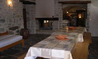 a large dining table with a white tablecloth and orange bowls is set in a stone room at La Bergerie