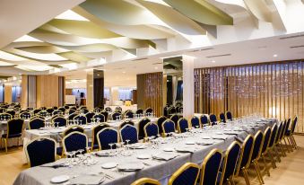 a large banquet hall with numerous tables and chairs arranged for a formal event , possibly a wedding reception at Hotel Olympia Valencia