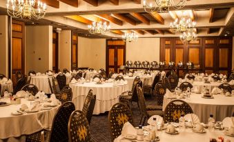a large , well - decorated banquet hall with multiple tables and chairs set up for a formal event at The Royal Hotel by Coastlands Hotels & Resorts