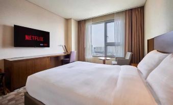 a large bed with a white sheet is in a hotel room with a window , chair , and television at Lotte City Hotel Ulsan