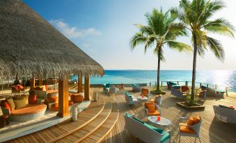 a tropical beach scene with a large lounge area and a view of the ocean at Dusit Thani Maldives