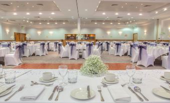 a large dining room with tables covered in white tablecloths and chairs arranged around them at DoubleTree by Hilton Swindon