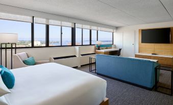 a hotel room with a large bed , couch , and dining table , all situated near a window overlooking the ocean at Delta Hotels Muskegon Convention Center