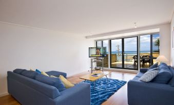 a living room with a blue couch , television , and sliding glass doors leading to an outdoor area at Grand Pacific Hotel