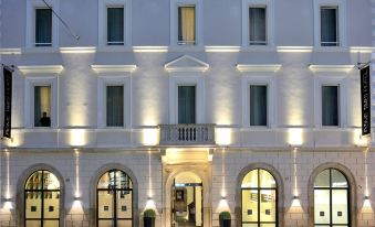 a white building with balconies and windows , situated in front of a street at night at Rome Times Hotel