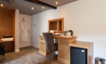 a wooden desk with a chair , mirror , and towel rack in a room with a sink and robe hanging on the wall at The Inn at Brough