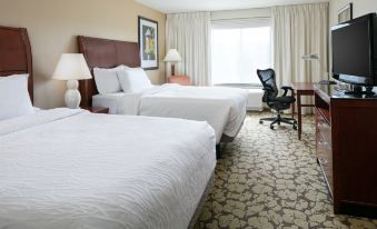 a hotel room with two beds , a desk , and a chair , all neatly arranged in the space at Hilton Garden Inn Omaha West
