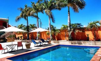 a large swimming pool with lounge chairs and palm trees in the background , under a clear blue sky at Cactus Inn Los Cabos