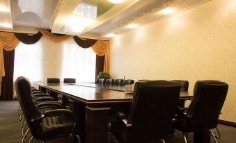 a conference room with a long wooden table surrounded by black chairs and gold curtains at Metropol Hotel