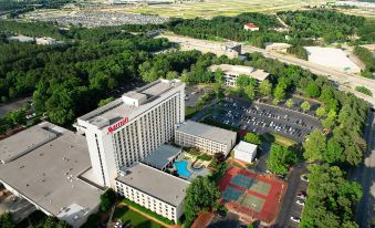 aerial view of a large hotel surrounded by a parking lot and trees , with a basketball court in the foreground at Atlanta Airport Marriott