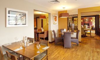 a dining room with wooden tables and chairs , as well as a bar area with wine glasses at Premier Inn Rochester