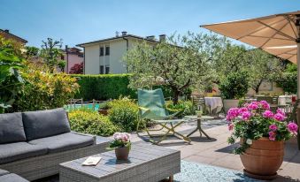 a backyard with a patio area featuring outdoor furniture , potted plants , and a swimming pool at Hotel San Marco