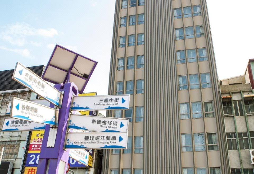 a tall building with a blue sign on the side and a street sign in front at Airline Inn Kaohsiung Station