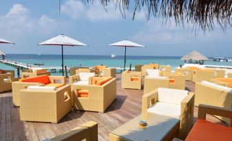 a tropical outdoor setting with several lounge chairs and umbrellas , providing a comfortable space for relaxation and socializing at Eriyadu Island Resort