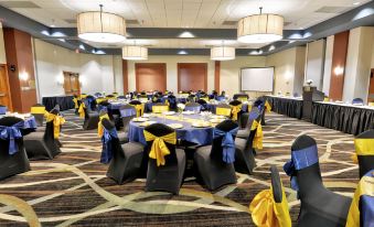 a well - decorated banquet hall with tables covered in blue and yellow tablecloths , chairs arranged around them , and a projector screen at at Holiday Inn ST. Petersburg N- Clearwater