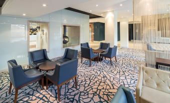 a modern hotel lobby with blue and gray geometric patterned carpet , several chairs and tables arranged around it at Crowne Plaza Stratford Upon Avon