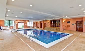 a large indoor swimming pool with a tiled floor and white walls , surrounded by windows and stairs at Homewood Suites by Hilton Stratford