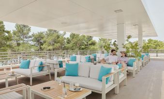 a group of people sitting outside on a patio , enjoying the outdoors and each other 's company at Bluesun Hotel Elaphusa