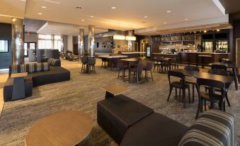 a large , modern lounge area with multiple couches , chairs , and tables , as well as a bar in the background at Courtyard Bay City