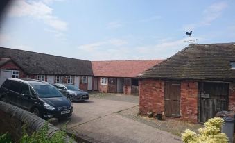 a courtyard with two buildings , one on the left side and the other on the right side , surrounded by a brick wall at Church Farm Accomodation