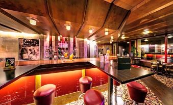 a modern bar with a wooden ceiling , a long bar counter , and several stools for patrons to sit on at Berghotel Bastei