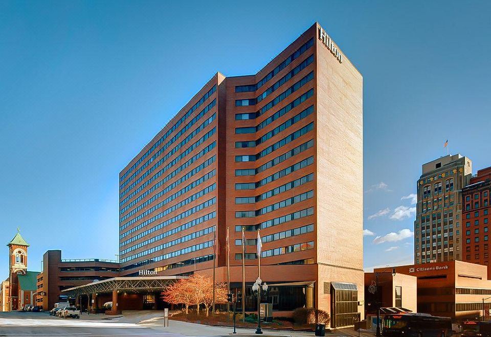 a large brick building with a blue sign on top , located in a city setting at Hilton Albany