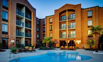 a large swimming pool is surrounded by tall buildings and an outdoor seating area with tables and chairs at Courtyard New Bern