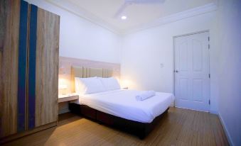 a white bedroom with a large bed , a closet , and a door leading to a bathroom at Keyla Inn