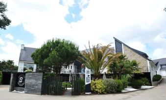 a modern house with a black fence and a sign on the side , surrounded by trees at Logis Golfe Hotel