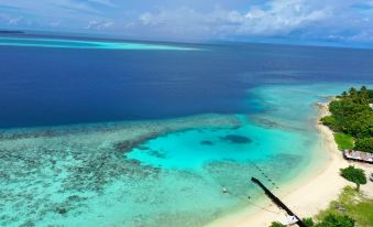 aerial view of a beautiful blue ocean with a sandy beach and a boat in the distance at Liberty Guesthouse Maldives