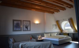 a modern bedroom with wooden beams on the ceiling , white walls , and a bed with grey bedding at Avenue Hotel