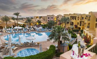 a resort with a large pool surrounded by multiple buildings and palm trees , creating a tropical atmosphere at Three Corners Rihana Resort El Gouna