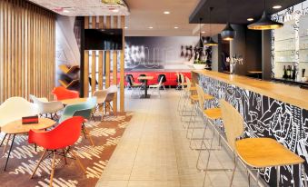 a modern lounge area with colorful chairs and a bar counter , featuring graffiti on the walls at Ibis de Panne