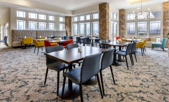 a dining room with a table surrounded by chairs , and a kitchen area with multiple stools at HIlton Garden Inn Roanoke