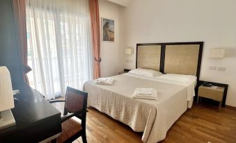 a hotel room with a large bed , wooden floor , and a window overlooking the city at Hotel Joli