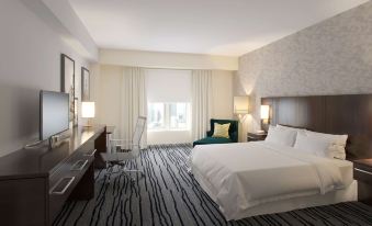 a modern hotel room with white bedding , black and white striped carpet , and a large window at The Mosey Buffalo Williamsville, Tapestry Collection by Hilton