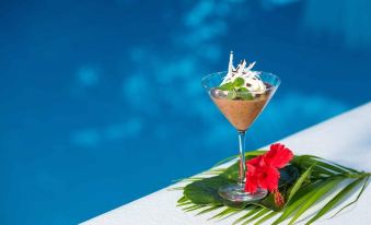 a cocktail glass with a fruit garnish is placed on a table next to a pool at Navutu Stars Resort